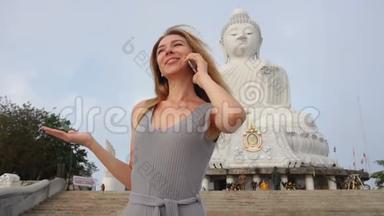 泰国佛像附近的一位慢动作旅游女士在智能手机上聊天